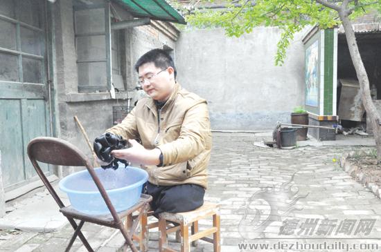 吳洪飛坐在凳子上洗衣服。記者 李靜 攝